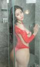 A woman in a red bathing suit standing in a shower.