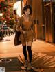 A woman in a brown dress is walking down the street.