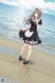 A woman in a maid outfit standing on a beach.