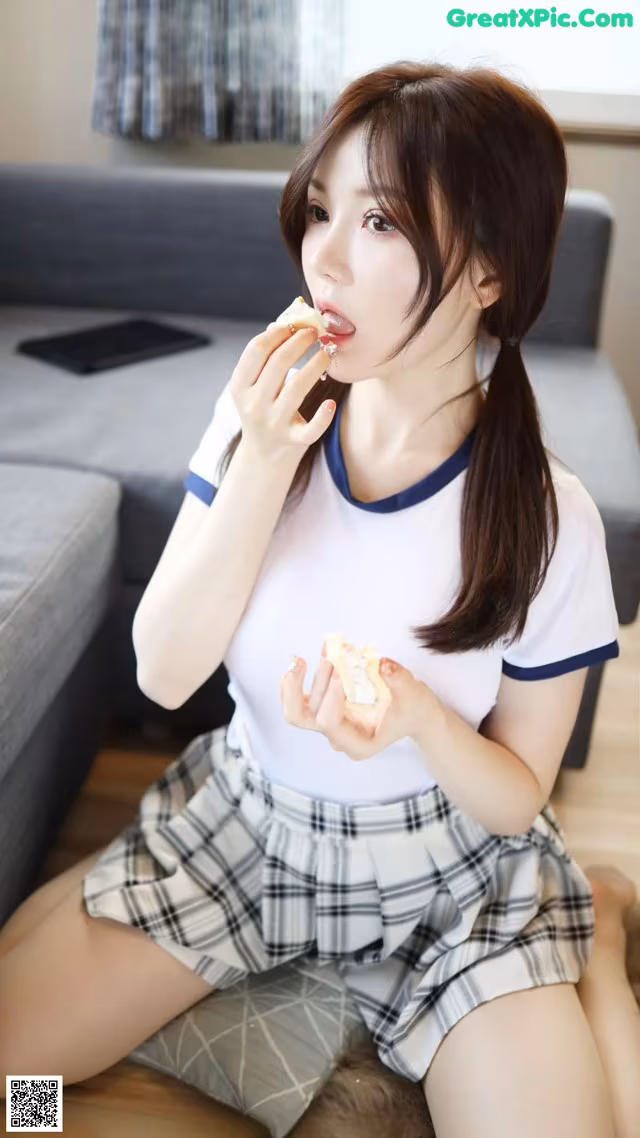 A woman sitting on the floor eating a piece of food.