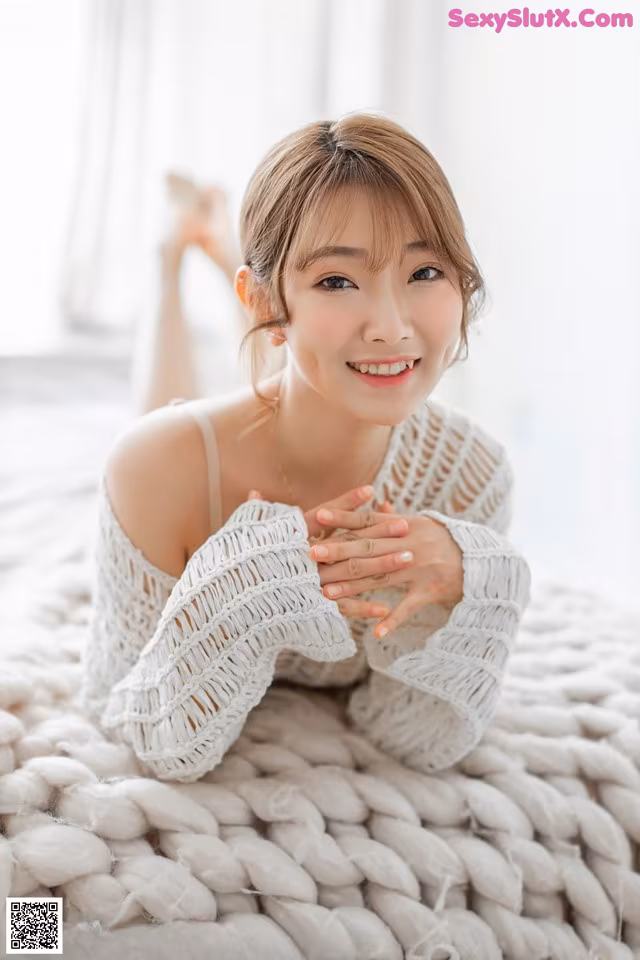 A woman laying on top of a bed covered in a blanket.