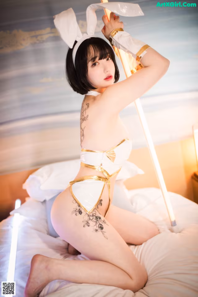 A woman in a bunny costume sitting on a bed.