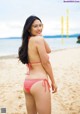 A woman in a pink bikini standing on a beach.