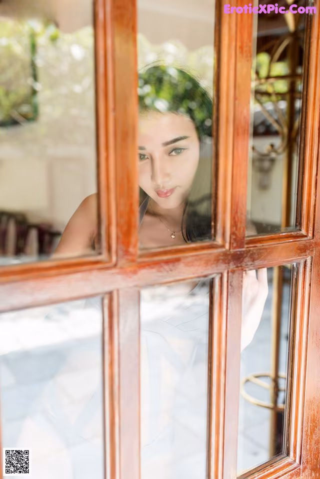 A woman looking out of a window at the camera.