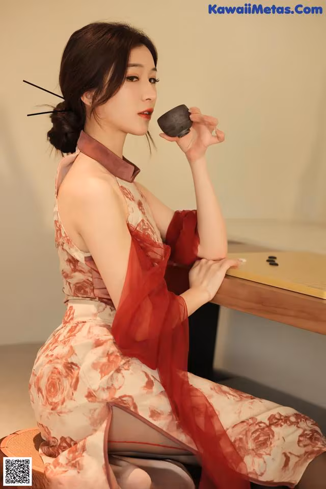 A woman in a red and white dress sitting at a table.