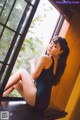 A woman sitting on a window sill in a black dress.