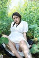 A woman in a white dress sitting in a field of yellow flowers.