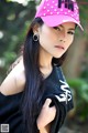 A woman with long black hair wearing a pink hat.