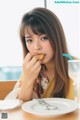 A woman sitting at a table eating a piece of food.