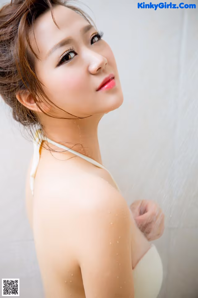 A woman in a white bikini standing in a shower.