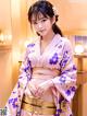 A woman in a purple kimono posing for a picture.