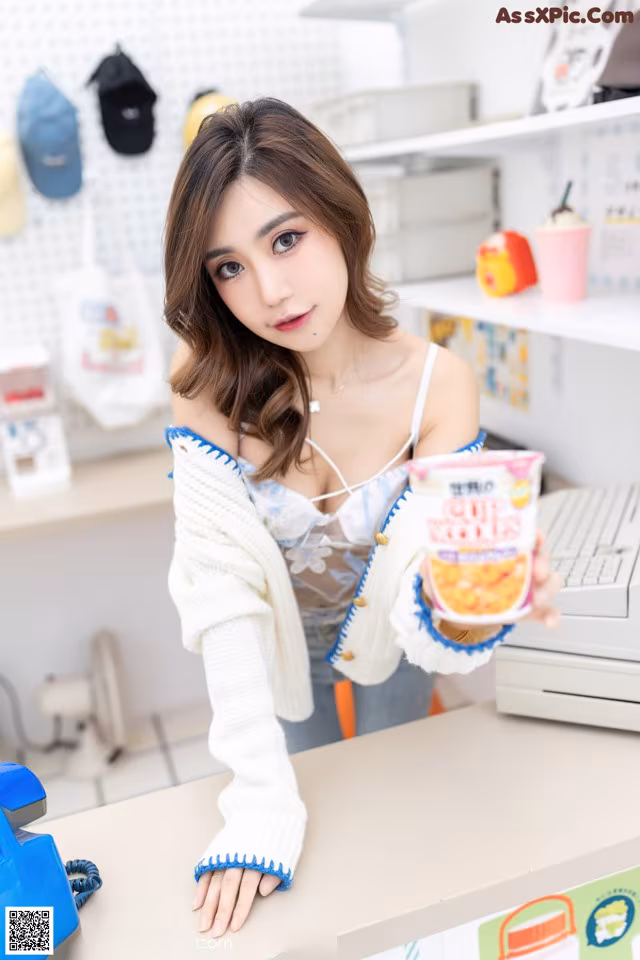 A woman sitting at a counter holding a cup of ice cream.